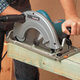 A 235mm 110v Circular Saw being used by a man to cut wood.